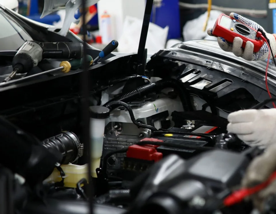 Technician diagnosing automotive wiring, fuses and relays with a digital multimeter